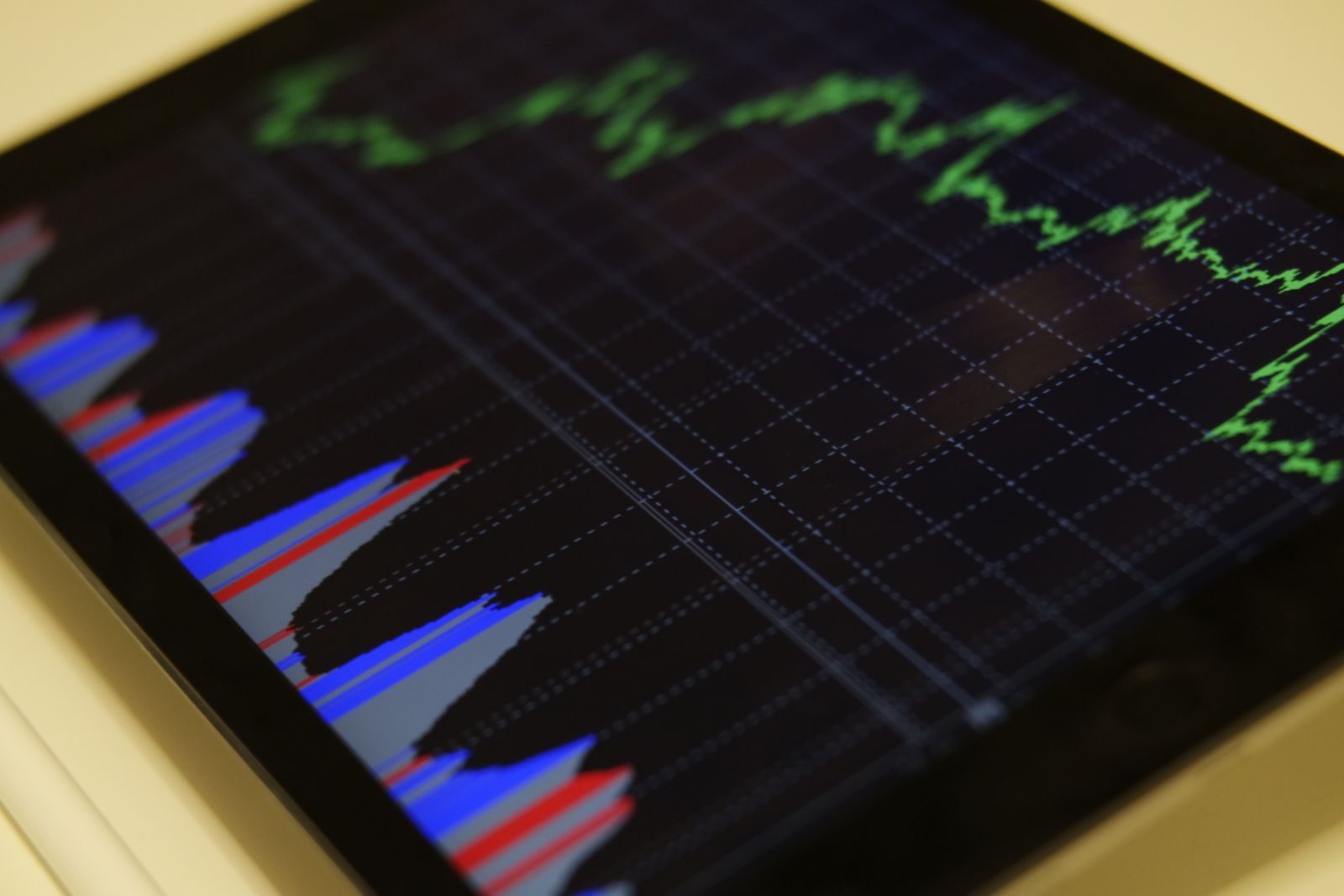 Laptop displaying financial line charts and performance graphs over a dark workspace